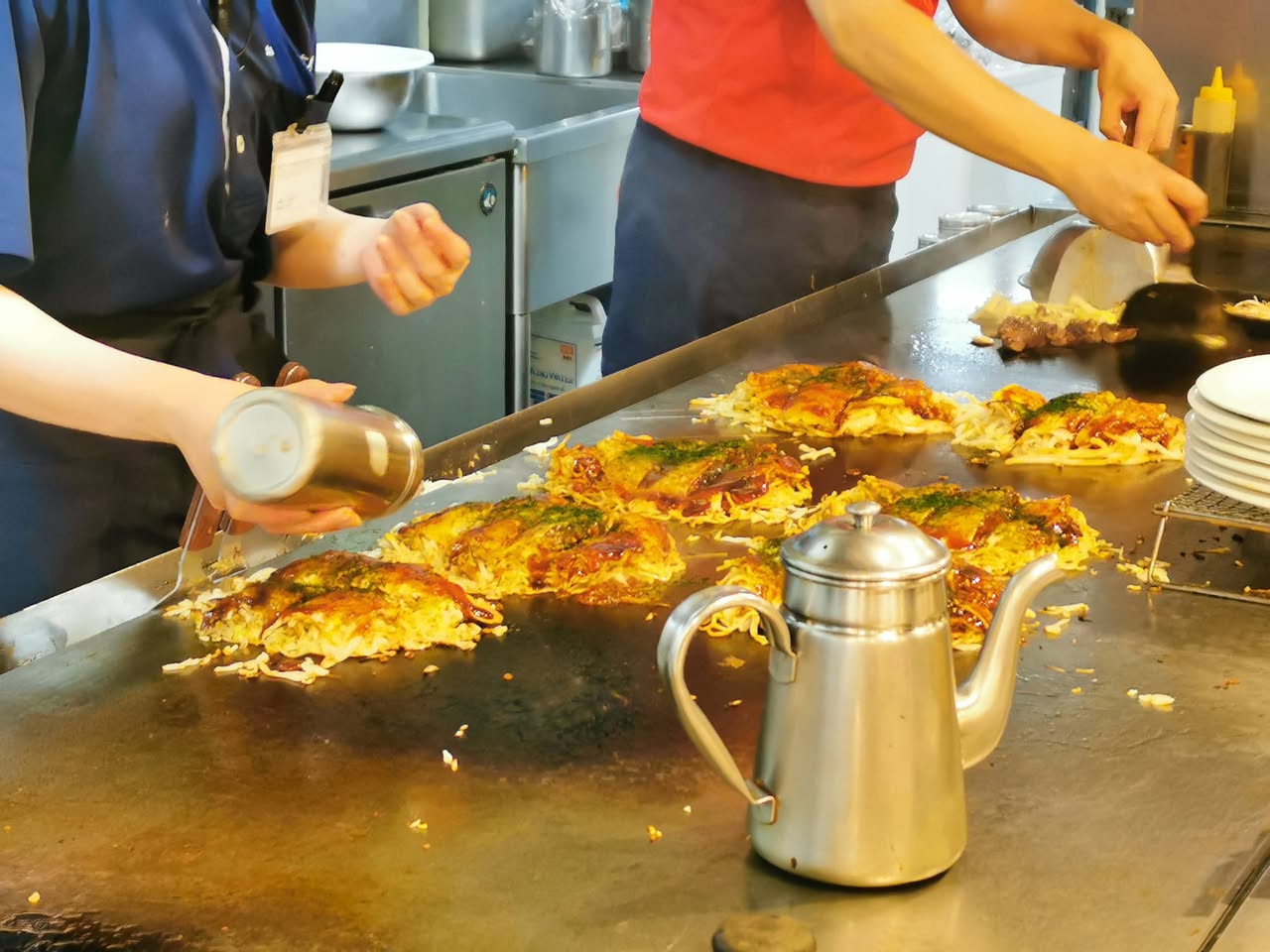 広島に到着後、お好み焼き店の鉄板で焼き上がるお好み焼き