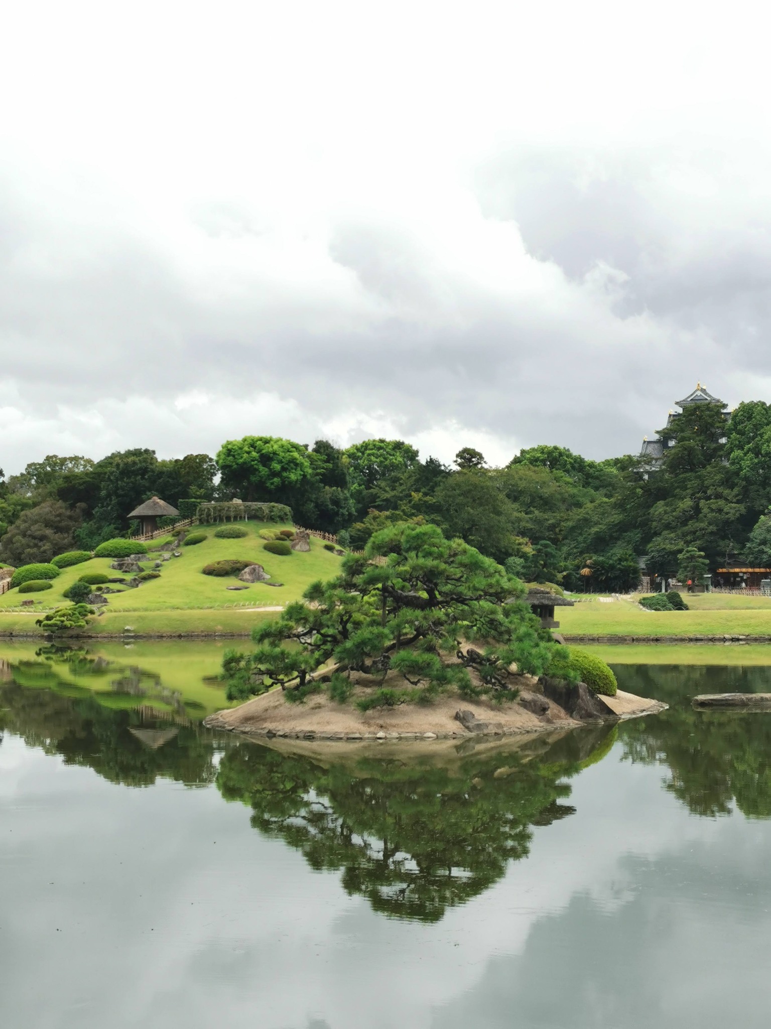 池に浮かぶ松の小島と岡山城を望む後楽園の風景